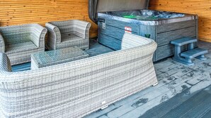 Puisesta materiaalista rakennettu huone, jossa on poreallas, rottinkihuonekaluja ja puulattia.