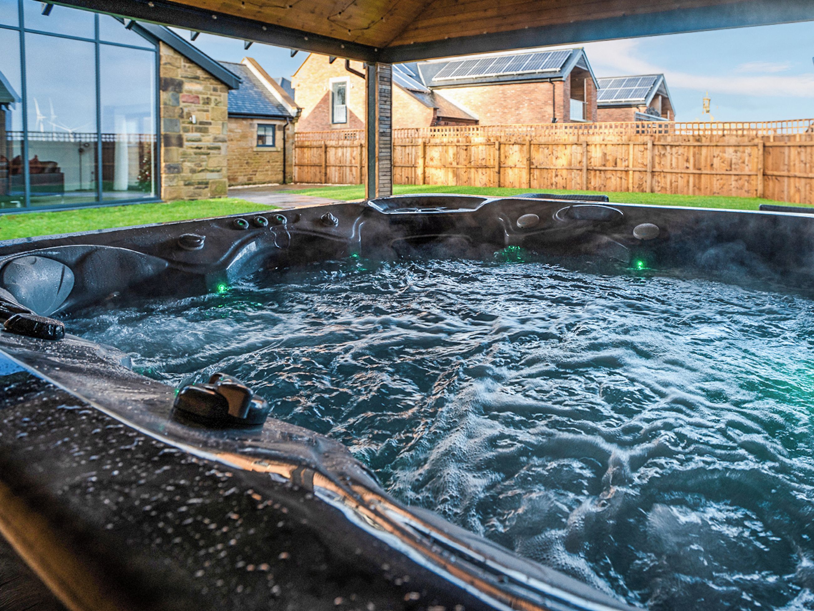 Un bain à remous avec vue sur une maison et une clôture en bois.