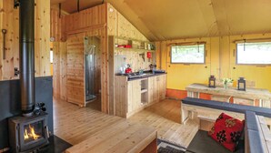 En mysig stuga med en central vedeldad kamin, ett köksområde och en matplats.