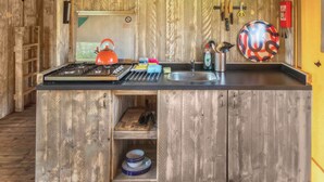 Una cucina rustica con mobili in legno, un fornello a gas, un bollitore e un lavello.