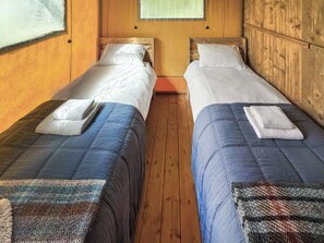 Een kamer met twee eenpersoonsbedden, houten wanden en een raam.