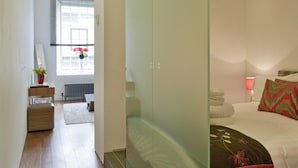 Habitación de hotel con cama, mesita de noche, lámpara y ventana con flores.