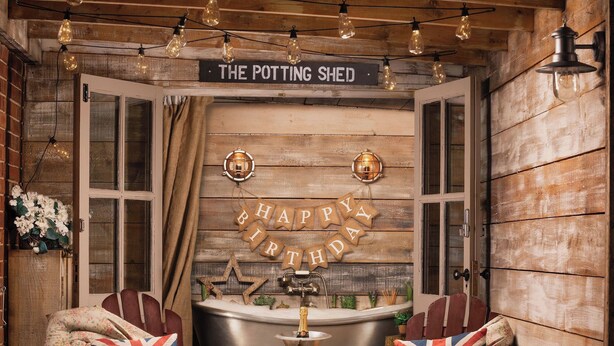 Una habitación acogedora con un letrero que dice 'The Potting Shed' y decoraciones de 'Happy Birthday'.
