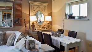 Un comedor con una mesa, sillas, un espejo y un ventanal.