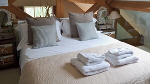 Un dormitorio con una cama grande, vigas de madera, una planta colgante y un espejo.