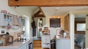 Una cocina funcional con cafetera, lavamanos y un pequeño comedor.