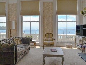 A spacious living room with a large window overlooking the sea, a sofa, a chair, and a coffee table. - Lady Astor Apartment-UKC95 (Plymouth)