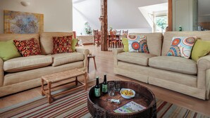 Un salon spacieux avec deux canapés, une table basse et, au fond, un coin repas.