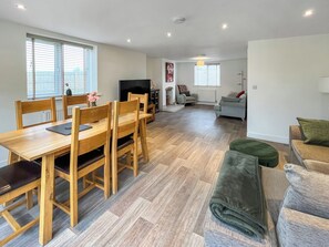 A spacious living area with a wooden dining table, a sofa, and a television. - 3 bedroom accommodation in North Scarle (North Scarle)