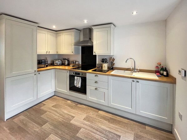 Une cuisine moderne avec des meubles blancs, une cuisinière noire et un plan de travail en bois.