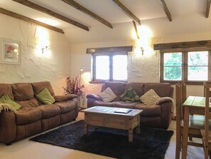 Ein gemütliches Wohnzimmer mit zwei braunen Ledersofas, einem Holztisch und einem schwarzen Teppich.
