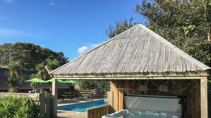 En trälusthus med pool och bubbelbad, omgivet av grönska.