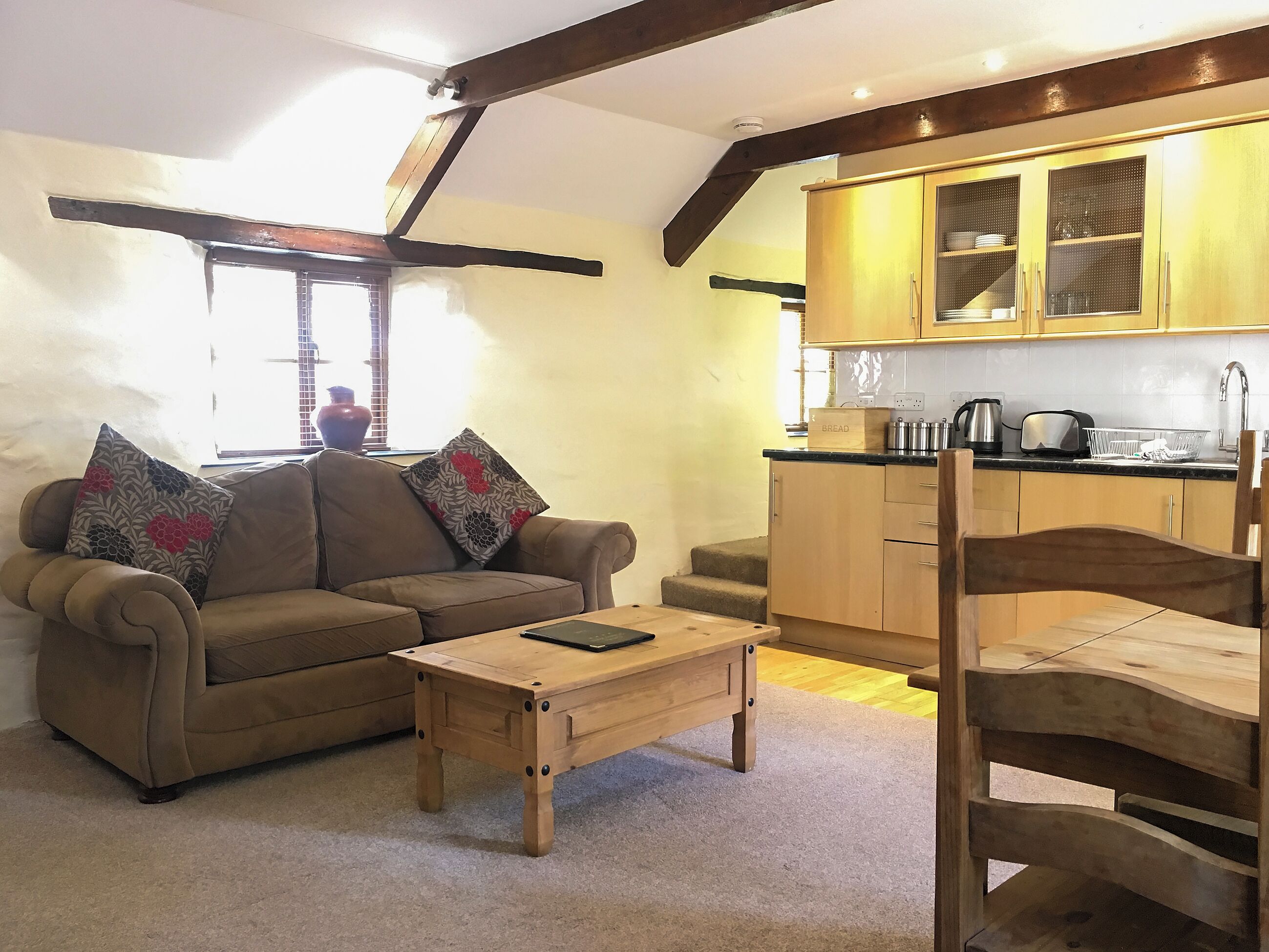 Una sala de estar con un sofá, una mesa de centro de madera y un comedor con una silla de madera.