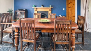 A dining room with a wooden table and chairs, a fireplace, a bookshelf, and a door. - 3 bedroom accommodation in Kidwelly (Kidwelly)