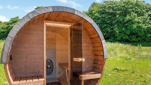 A wooden sauna structure with an open door, a bench, and a small table inside. - 3 bedroom accommodation in Kidwelly (Kidwelly)