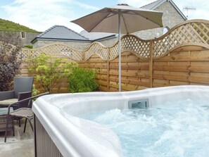 A hot tub with a wooden fence, a wicker chair, and an umbrella. - 2 bedroom accommodation in Kidwelly (Kidwelly)