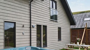 Ett hus med en bubbelpool på bakgården, en träterrass och ett picknickbord.