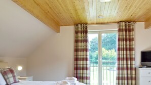 Une chambre à coucher avec un lit, une télévision, une table de chevet et une fenêtre avec des rideaux.