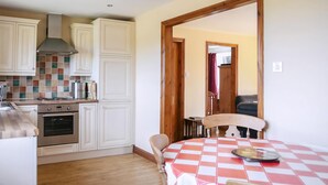 A kitchen with white cabinets, a stove, and a checkered tablecloth-covered table. - 2 bedroom accommodation in Bickley, near Malpas (Bickley, near Malpas)