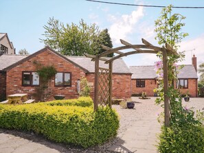 A brick cottage with a wooden pergola, a gravel path, and a yellow table. - 2 bedroom accommodation in Bickley, near Malpas (Bickley, near Malpas)