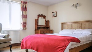 A bedroom with a wooden bed, a chair, a dresser, a mirror, and a window with curtains. - 2 bedroom accommodation in Bickley, near Malpas (Bickley, near Malpas)