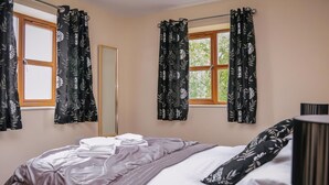 A bedroom with a bed, a window, and curtains.