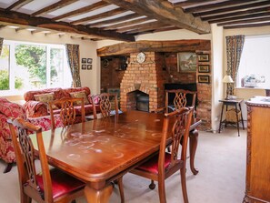 A dining area with a wooden table and chairs, a brick fireplace, and a sofa with patterned cushions.