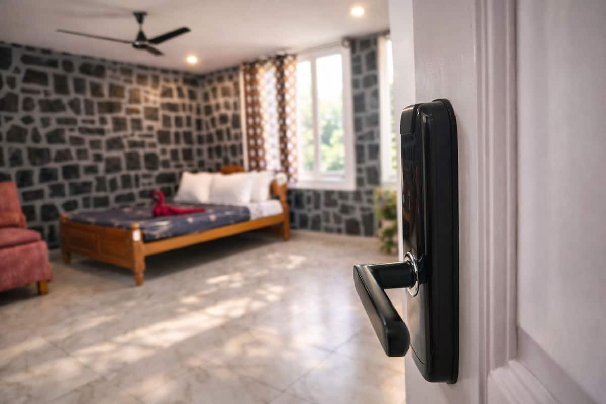 A bedroom with a stone wall, a bed, a ceiling fan, and a door with a handle.