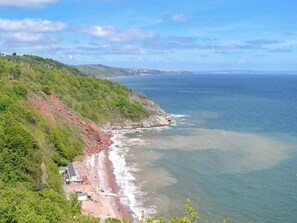 Vista costera con playa, acantilados rocosos y cielo despejado.