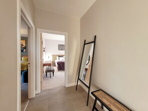 A hallway with a door leading to a bedroom. A mirror is propped against the wall, and a bench is placed near the door. - Marsh Marigold Cottage - UKC4642 (Dunholme, near Lincoln)