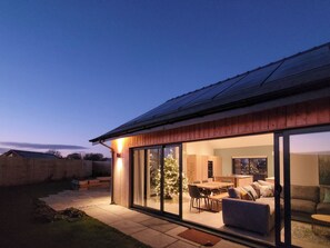 Een modern huis met een grote glazen deur die leidt naar een eetruimte en een woonkamer.