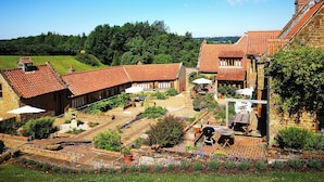 Um pátio com edifícios de tijolo, área de estar externa e vista da paisagem ao redor.