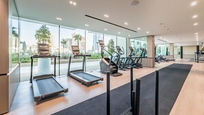 Een moderne sportschool met loopbanden, elliptische trainers en hometrainers. Grote ramen bieden uitzicht op een stadsgezicht.