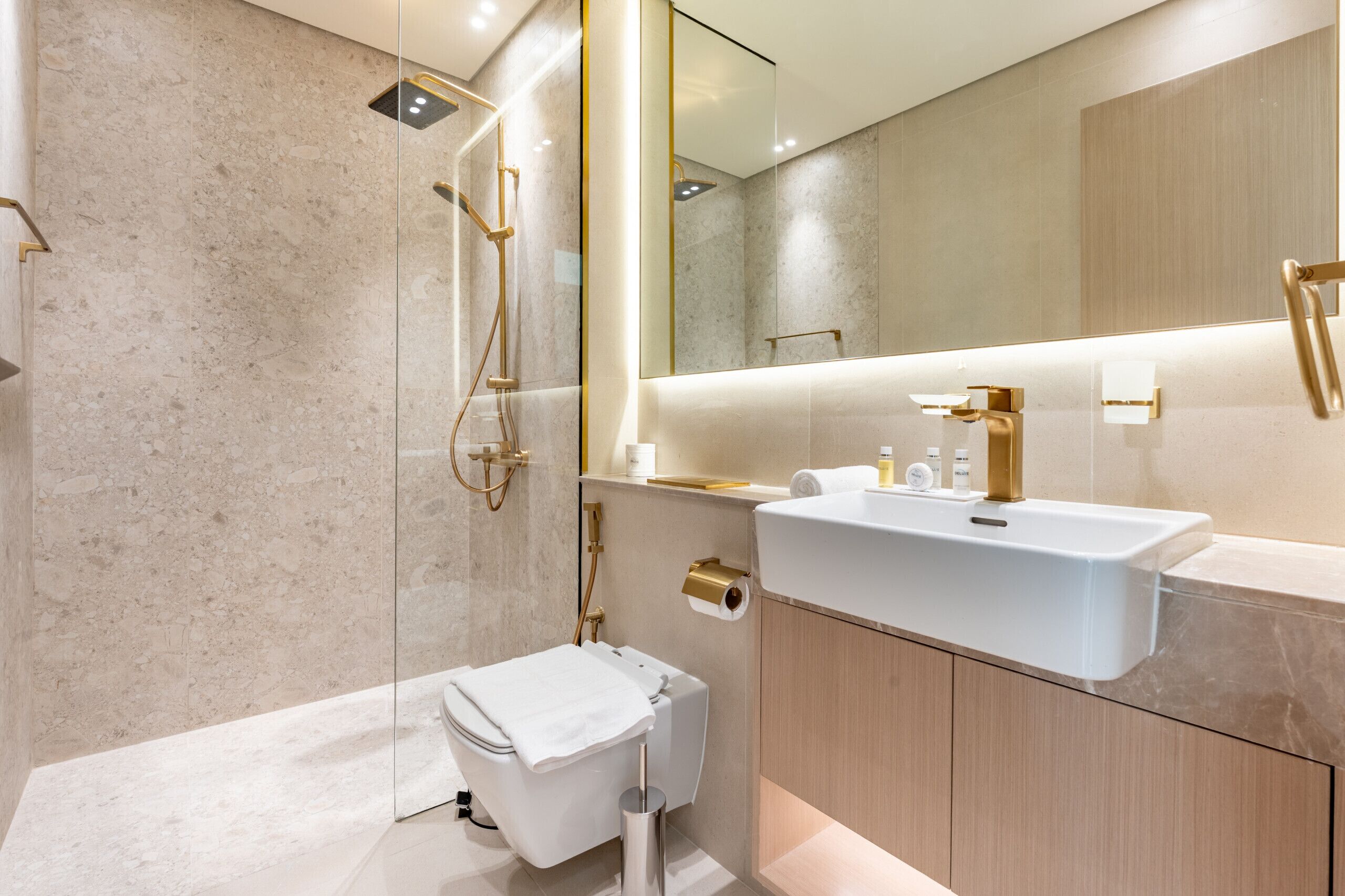 Ein modernes Badezimmer mit einer ein Glasfenster trennenden Duschkabine, einem weißen Waschbecken und Holzschränken.