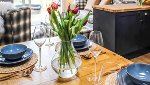 A dining table set with blue bowls, wine glasses, and a vase with tulips. - 2 bedroom accommodation in Rhayader and the Elan Valley (Rhayader and the Elan Valley)