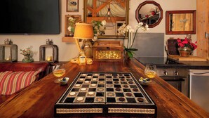 Une pièce avec une table en bois, un jeu d’échecs, des lampes décoratives et un grand miroir.
