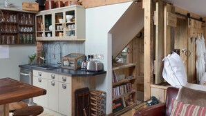 Une cuisine rustique avec des poutres en bois, une bibliothèque intégrée et un coin repas comprenant une table et un banc en bois.