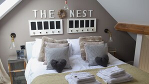 Una cama bien hecha con varias almohadas y un letrero que dice 'THE NEST'.