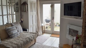 Una sala de estar acogedora con un sofá, un televisor, una chimenea y una puerta corrediza de vidrio que da a un patio.