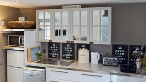 Una cocina moderna con armarios blancos, un microondas, un contenedor para pan, una tetera y un tostador.
