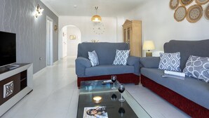 A modern living room with a sofa set, a coffee table, a TV, and decorative wall art. - Sunstay Adriana Flat II Fuengirola (Fuengirola)