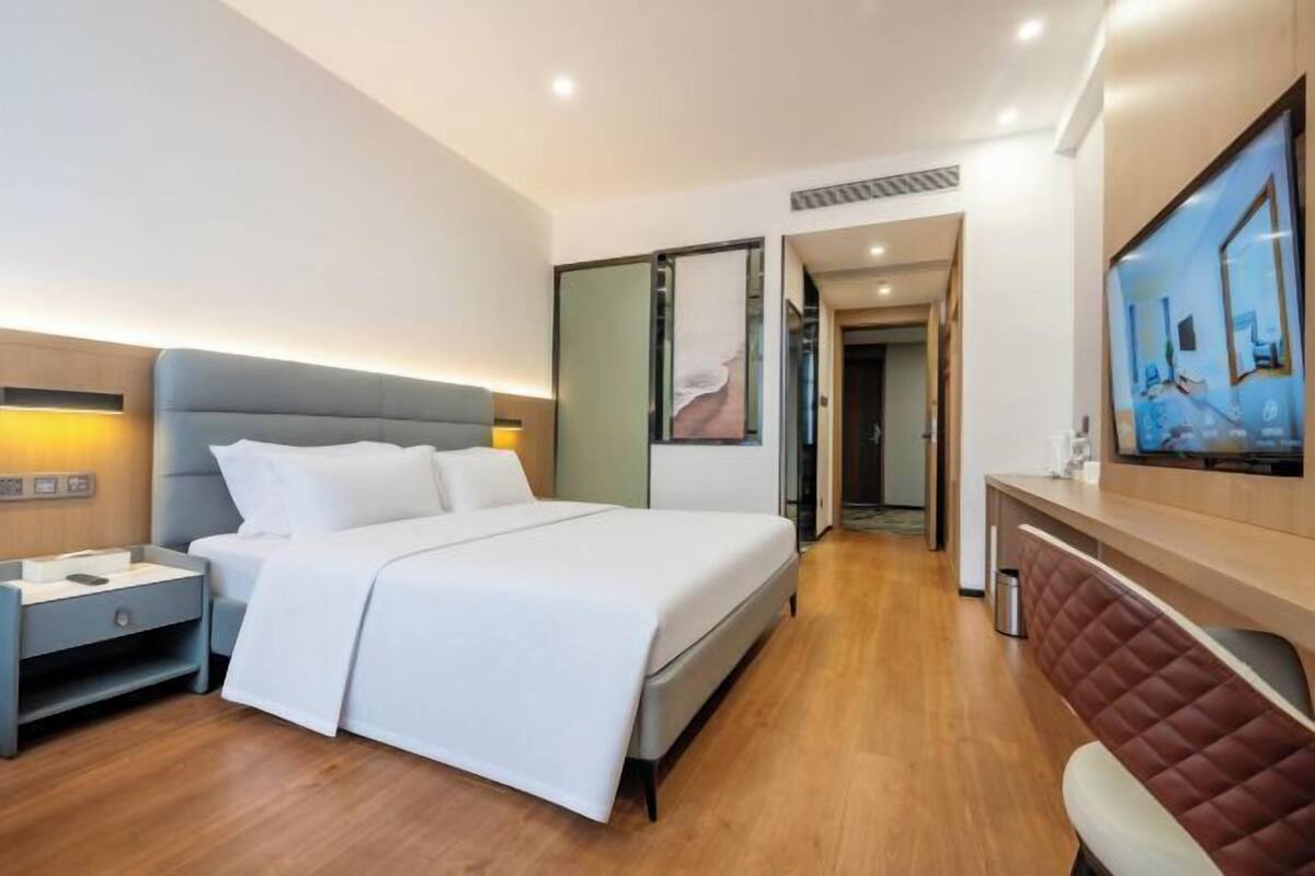 Een moderne hotelkamer met een groot bed, nachtkastjes, een bureau en een televisie.