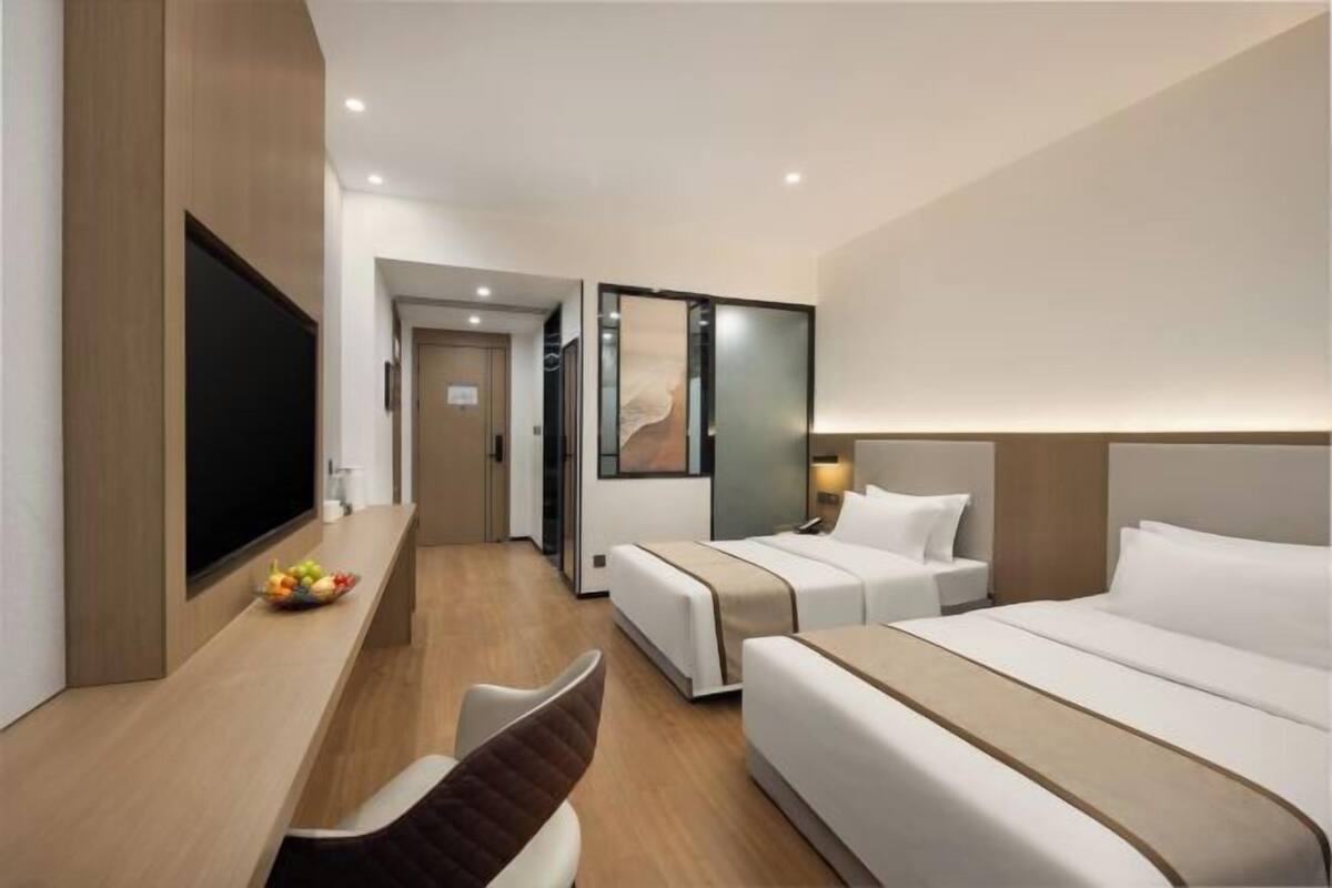 Hotelkamer met een bed, een bureau met een flatscreen televisie, een stoel en een kleine tafel met fruit.