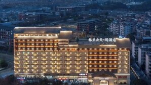 A multi-story hotel with a prominent entrance, numerous windows, and a well-lit facade. - JingdezhenGrand Skylight Yue Hotel (Guyao Folk Custom Expo Area) (Jingdezhen)
