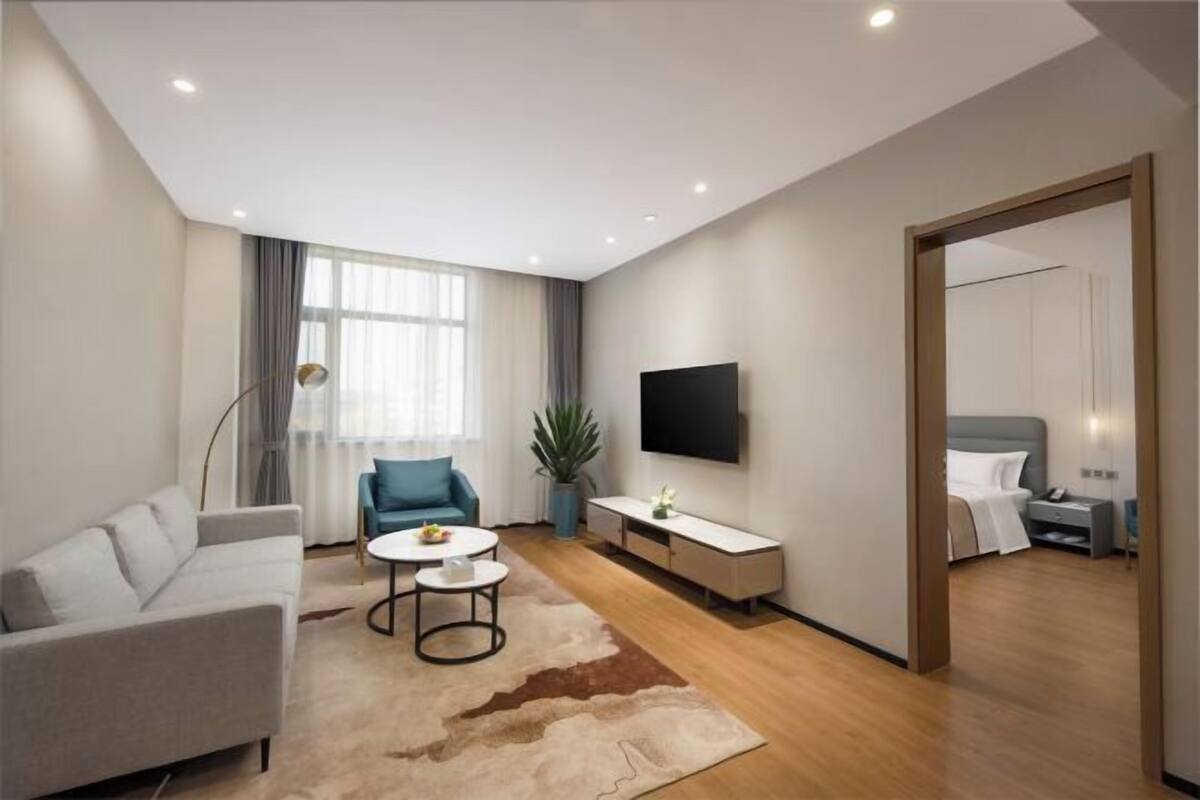Een moderne woonkamer met een bank, salontafel, televisie en een plant.