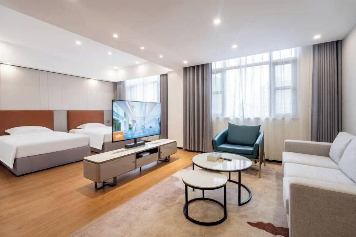Een moderne hotelkamer met een bed, een televisie, een bank, een salontafel en een bureau.
