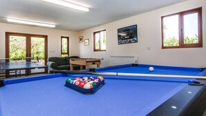 A pool table with a ball rack, a foosball table, and a ping pong table in a room with windows and a radiator. - The Old Stables - UKC4806 (Bishops Nympton)