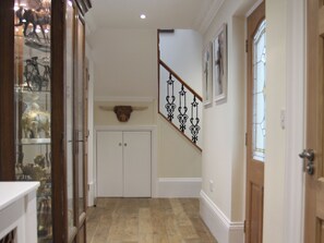 Un couloir avec un escalier en bois, une porte dotée d’un panneau de verre et une décoration murale représentant une tête de taureau.