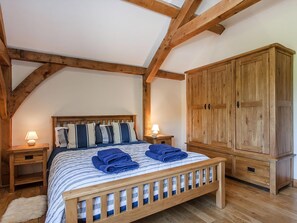 A bedroom with a wooden bed, a wardrobe, and a nightstand with a lamp. - Orchard Cottage - UKC4805 (Bishops Nympton)
