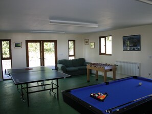 Une pièce équipée d’une table de ping-pong, d’un baby-foot et d’une table de billard.